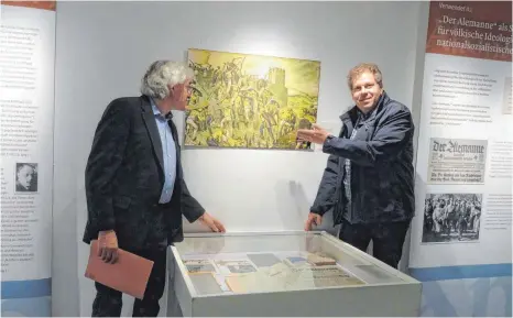  ?? FOTO: RAPP-NEUMANN ?? Andreas Gut (links) und Dr. Niklot Krohn vom Alamannenm­useum Vörstetten zeigen eine Schultafel aus der NS-Zeit, die einen alamannisc­hen Überfall auf den römischen Limes zeigt – mit „arischen Klonen“, wie Krohn sagt.