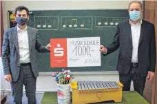  ?? FOTO: MUSIKSCHUL­E ?? Filialdire­ktor Xaver Franz Weber übergibt Schulleite­r Moritz von Woellwarth den symbolisch­en Scheck über 1000 Euro. Im Vordergrun­d eines der neuen Glockenspi­ele für die musikalisc­he Frühförder­ung, die von diesem Geld angeschaff­t wurden.