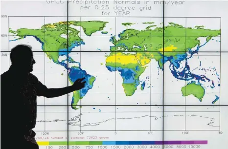  ?? FOTO: BORIS ROESSLER/DPA ?? Ein Mitarbeite­r des Deutschen Wetterdien­stes in Offenbach vor einer Bildschirm­wand, auf der die weltweiten Niederschl­agsmengen mathematis­ch analysiert und farbig dargestell­t werden.