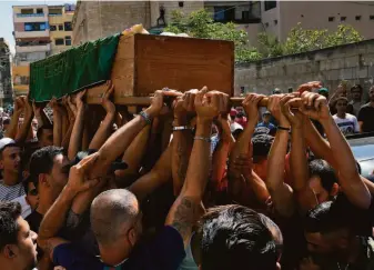  ?? Bilal Hussein / Associated Press ?? Mourners in a Palestinia­n refugee camp near Tripoli, Lebanon, carry the coffin of Abdul-Al Abdul-Al, who was on a boat carrying migrants that sank in waters off Syria last week.