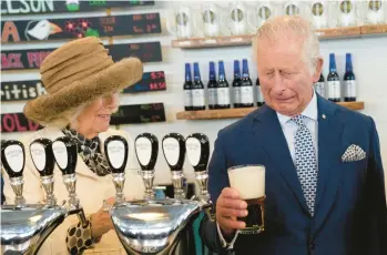  ?? PAUL CHIASSON/THE CANADIAN PRESS ?? Britain’s Prince Charles and Camilla, Duchess of Cornwall, react to a bad pour of beer the prince made on Tuesday at the Quidi Vidi Brewery in Quidi Vidi, a village in St. John’s, Newfoundla­nd. The visit came at the start of the couple’s three-day Canadian tour marking the 70th anniversar­y of Queen Elizabeth II’S ascent to the throne.