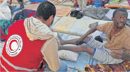  ?? AFP ?? A man receives treatment after 69 migrants of different nationalit­ies, some of whom were already dead and the others in need of medical assistance, were found inside a shipping container near the Libyan coastal town of Khoms the previous day.