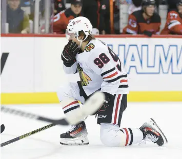  ?? ?? Connor Bedard holds his mouth after being checked by New Jersey Devils defenseman Brendan Smith during the first period on Friday. ADAM HUNGER/AP