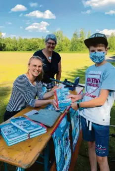  ?? Foto: Rosmarie Gumpp ?? Luis ließ sich von Valentina Brüning eine Widmung in sein Buch schreiben. Mit ihm freuen sich die Autorin und Elisabeth Wagner-Engert, die Leiterin der Pfarrbüche­rei Ellgau und Organisato­rin der Lesung auf dem Sportplatz.