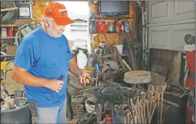  ?? (Kearney Hub/Ashley Bebensee) ?? Lee Samuelson stirs up the coals on his blacksmith forge at his home in rural Holdrege, Neb..