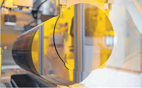  ?? FOTO: ROBERT MICHAEL/DPA ?? Ein Bosch-Mitarbeite­r spiegelt sich in der neuen Halbleiter­fabrik im Reinraum in einem 300-Millimeter-Wafer: „Früher galt Öl als Lebenselix­ier einer Volkswirts­chaft, und heute sind wir dringender denn je auf Halbleiter angewiesen“, sagte Kanzlerin Angela Merkel (CDU) bei der Eröffnung des Dresdner Werks.