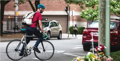  ?? ASHLEE REZIN/SUN-TIMES ?? A bicyclist stops to visit a memorial at the corner of North Winthrop and West Leland avenues, where a 3-year-old was killed when her mother’s bicycle was hit by a semi.