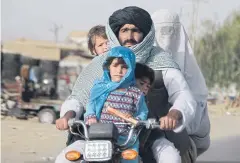  ?? AFP ?? A burqa-clad woman travels with her family on a motorbike along a road in Kandahar on Saturday.