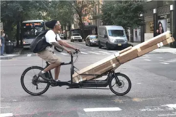 ??  ?? A person drives a cargo bike with long packages down 2nd Avenue in New York City. New orders, production and employment all grew solidly compared to July, with contributi­ons from 16 of the 18 industries surveyed, and especially large gains from the six big industries, according to the Institute for Supply Management’s closely-watched survey. — Reuters photo