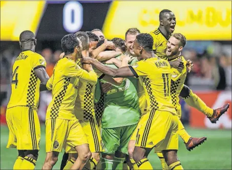  ?? [DANNY KARNIK/THE ASSOCIATED PRESS] ?? Teammates mob goalie Zack Steffen, in green, following the Crew’s dramatic win against Atlanta United in the knockout round of the MLS playoffs Thursday night.