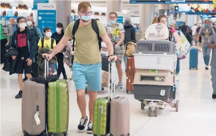  ?? MARTA LAVANDIER/AP ?? A family and their pets walk Monday through Miami Internatio­nal Airport. AAA expects to see a huge spike in holiday travel this year.