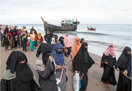  ?? — ap ?? Perilous journey: a group of rohingya walking to a temporary shelter after they landed on their wooden boat in North aceh, Indonesia.