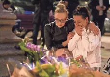  ??  ?? LEON NEAL, GETTY IMAGES A woman is consoled amid floral tributes after an evening vigil outside the town hall Tuesday in Manchester, England.