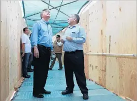  ?? Baja California governor’s office ?? B A JA California Gov. Francisco Vega de Lamadrid, left, and his public works secretary, Manuel Guevara, enter the provisiona­l border-crossing structure.