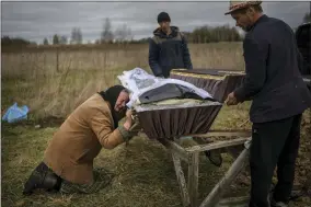  ?? RODRIGO ABD/ASSOCIATED PRESS ?? Nadiya Trubchanin­ova, 70, cries while holding the coffin of her son Vadym, 48, who was killed by Russian soldiers last March 30in Bucha, during his funeral in the cemetery of Mykulychi, on the outskirts of Kyiv, Ukraine, Saturday, April 16, 2022. After nine days since the discovery of Vadym’s corpse, finally Nadiya could have a proper funeral for him. This is not where Nadiya Trubchanin­ova thought she would find herself at 70 years of age, hitchhikin­g daily from her village to the shattered town of Bucha trying to bring her son’s body home for burial.