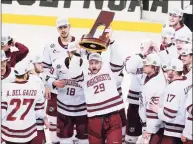  ?? Keith Srakocic / Associated Press ?? UMass’ George Mika (29) holds the NCAA trophy over his head as he skates with the team to celebrate their 5-0 win over St. Cloud State in the Frozen Four championsh­ip game Saturday.