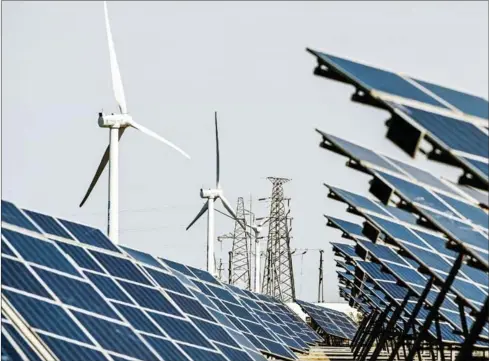  ?? AFP ?? Solar panels and wind turbines work in an integrated power station in Jiangsu province, China, last year. Solar panels in some places make cheaper electricit­y at noon, but at night the cost is infinite. That is why across Europe, the higher the share of wind and solar, the higher the household cost of electricit­y.