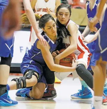  ?? LUIS SÁNCHEZ SATURNO/THE NEW MEXICAN ?? Lovington’s Tayler Valencia, left, and Española’s Leah DeAguero, right, fight over a loose ball during the second quarter of Tuesday’s Class AAAAA State Basketball Tournament quarterfin­al in The Pit in Albuquerqu­e.