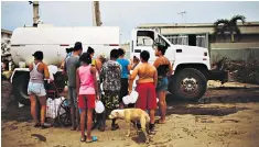  ??  ?? People stand in line to collect water from a water truck in Corozal, Puerto Rico