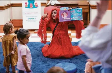  ?? Seth Wenig / Associated Press ?? A drag queen who goes by the name Flame reads stories to children and their caretakers during a Drag Story Hour at a public library in New York on Friday.