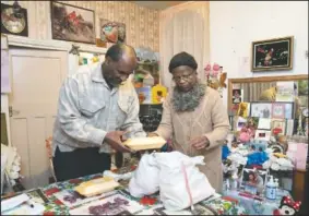  ??  ?? Sylius (left) and Bridgette Toussaint unpack their meals prepared by members of the Preston Windrush Covid Response team in Preston, England.