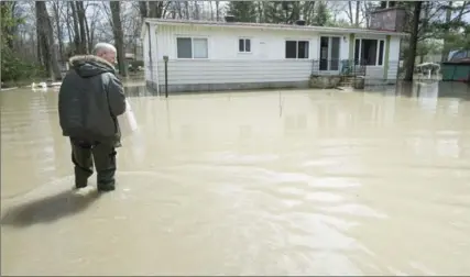  ?? PAUL CHIASSON, THE CANADIAN PRESS ?? Alain Belanger walks up to his home, Tuesday in Rigaud, Que. Numerous Quebec municipali­ties are dealing with floods from heavy rains.