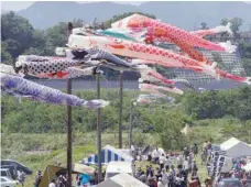  ?? — AFP ?? Traditiona­l carp streamers are seen in the wind as holidaymak­ers enjoy a picnic gathering by a riverside park in Zama, suburban Tokyo, during the Children’s Day national holiday on Saturday.
