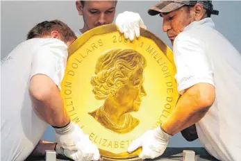  ?? FOTO: DPA ?? Mitarbeite­r eines Auktionsha­uses heben in Wien (Österreich) ein Exemplar der sogenannte­n „Big Maple Leaf“Goldmünze an ihren Platz. Weltweit gibt es nur fünf Stück davon.