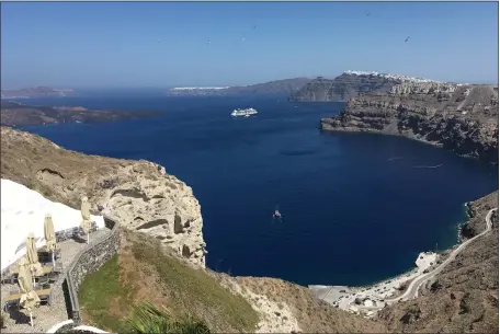  ?? JANET PODOLAK — FOR THE-NEWS-HERALD ?? Santorini’s vast 8-by-5-mile volcanic caldera dwarfs the 14-deck Celebrity Apex anchored off shore. A serpentine road winds down to the sea in the foreground as white-washed village houses frost distant clifftops.