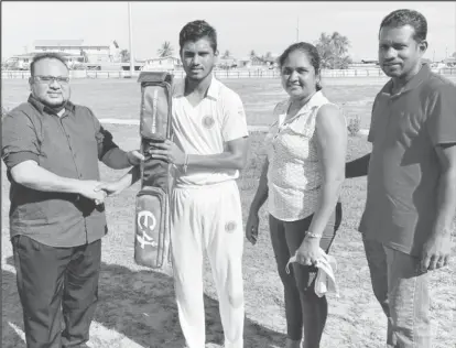  ?? ?? Alvin Mohabir (second from left) receives the bat from GCB president, Bissoondya­l Singh in the presence of Mohabir’s parents.