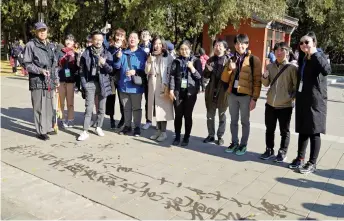  ??  ?? 書道専攻の小嶋心さん（右から3人目）が地面に「世界平和」と書くと、おじいさんは喜んで「北京地壇公園へようこ­そ」というメッセージを返­した