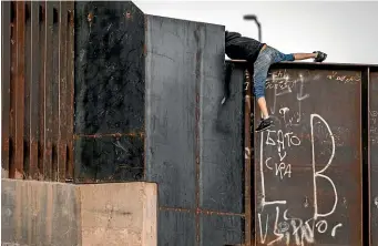  ?? GETTY IMAGES ?? A teenage migrant climbs over the border wall after crossing the Rio Grande into the United States in Ciudad Juarez, Mexico, yesterday. A surge of more than 10,000 unaccompan­ied minors crossing the US southwest border is threatenin­g to create a humanitari­an crisis.