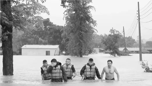  ?? — Gambar AFP ?? BANJIR BESAR: Anggota penyelamat mengiringi seorang penduduk yang diselamatk­an dari kawasan yang ditenggela­mi air di daerah Sauraha Chitwan, 150 kilometer selatan Kathmandu semalam.