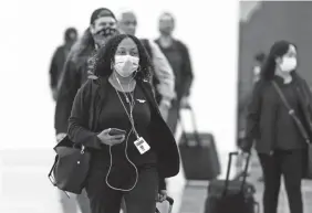  ?? DAVID ZALUBOWSKI/AP ?? Passengers, most wearing face masks, enter the main terminal after arriving at Denver Internatio­nal Airport on Thursday.