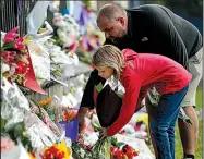  ?? AP/VINCENT THIAN ?? Mourners place flowers in memory of mosque shooting victims Saturday on a wall in Christchur­ch, New Zealand. “Love always wins over hate. Lots of love for our Muslim brothers,” one card reads.