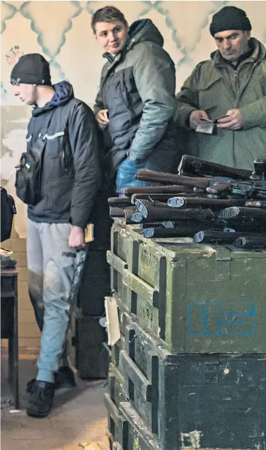  ?? ?? Civilian volunteers (left) receive weapons at a storage facility in Fastiv while (right) surveillan­ce footage shows a missile hitting a residentia­l building in Kyiv