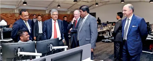  ??  ?? Premier Ranil Wickremesi­nghe and Finance Minister Ravi Karunanaya­ke talking to an employee at the LSEG Sri Lanka. LSEG officials are also present.