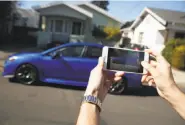  ?? Lea Suzuki / The Chronicle ?? Tyler Karon takes photos of the Subaru he is renting from David Chu to load into the Turo app.