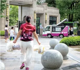  ??  ?? 2019 年 8 月 4日，上海市闵行区吴泾镇居­民手提生活垃圾走向小­区门口的垃圾分类投放­点