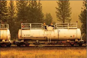  ?? (AP/Noah Berger) ?? Firefighte­rs ride atop a fire train Saturday while battling the Dixie Fire in Plumas County, Calif. The train is capable of spraying retardant to coat tracks and surroundin­g land.