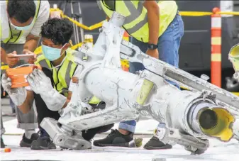  ?? Azwar Ipank / AFP / Getty Images ?? Investigat­ors examine a landing gear assembly recovered from the Lion Air jetliner that crashed Oct. 29 into the Java Sea after takeoff from Jakarta, killing all 189 people on board.