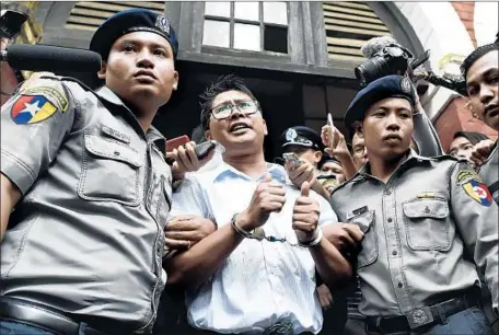  ?? Photograph­s by Ye Aung Thu AFP/Getty Images ?? REUTERS JOURNALIST Wa Lone is escorted by police after being sentenced last week in Yangon to seven years in jail for violating Myanmar’s Official Secrets Act. He and another reporter found evidence that 10 Rohingya men were executed and buried in a mass grave.