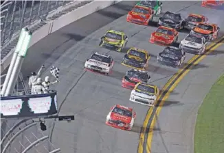  ??  ?? Ryan Reed takes the checkered flag to win Saturday’s NASCAR Xfinity series race at Daytona Internatio­nal Speedway. Wrecks kept several cars from being able to finish the season opener.