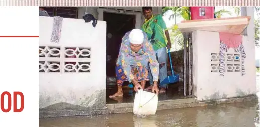  ?? PIC BY NOR FARHANI CHE AD ?? A woman and her son cleaning the compound of their house following a flood in Sungai Petani yesterday.