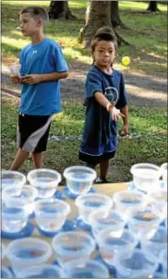  ??  ?? Charlie Stehlik tosses a ping-pong ball at plastic fishbowls looking to win a goldfish.