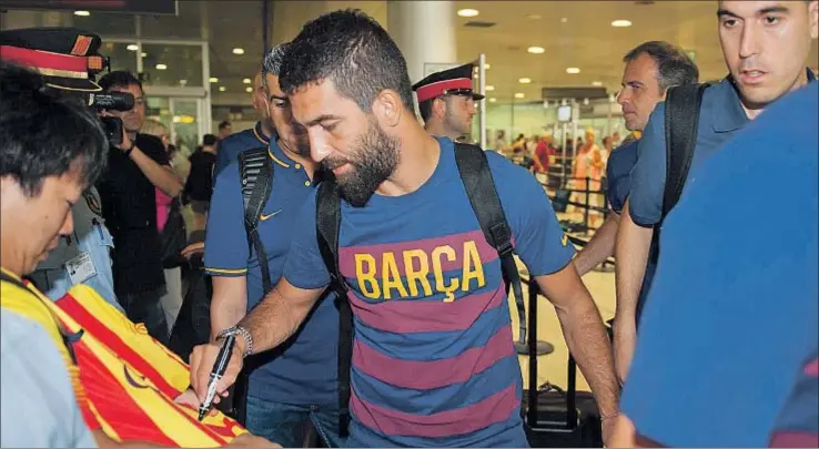  ?? GEMMA MIRALDA ?? Arda Turan, el último fichaje del Barcelona, firma un autógrafo en una camiseta antes de embarcar con destino a Los Ángeles