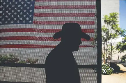  ?? Photos by Jae C. Hong, The Associated Press ?? Iraq War veteran Vernon Poling, 44, walks through a courtyard past a giant American flag at Potter’s Lane, an apartment complex made out of recycled shipping containers in Midway City, Calif.