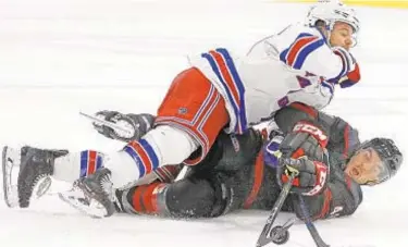  ?? AP ?? Hurricanes’ Jordan Martinook keeps eye on puck despite pressure from Rangers’ Tony DeAngelo.