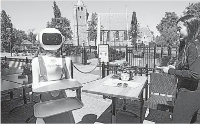  ?? PETER DEJONG/AP ?? Leah Hu guides a robot used as a greeter and server May 27 at the Royal Palace restaurant in the Netherland­s.