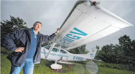  ?? FOTO: MARIJAN MURAT/DPA ?? Pilot Frank Kasparek steht neben einem Flugzeug zur Hagelabweh­r. Bildet sich in Württember­g ein Unwetter, steigt er mit seiner Maschine auf, um Schlimmere­s zu verhindern. Ob Hagelflieg­er wie er das wirklich können, ist jedoch umstritten.